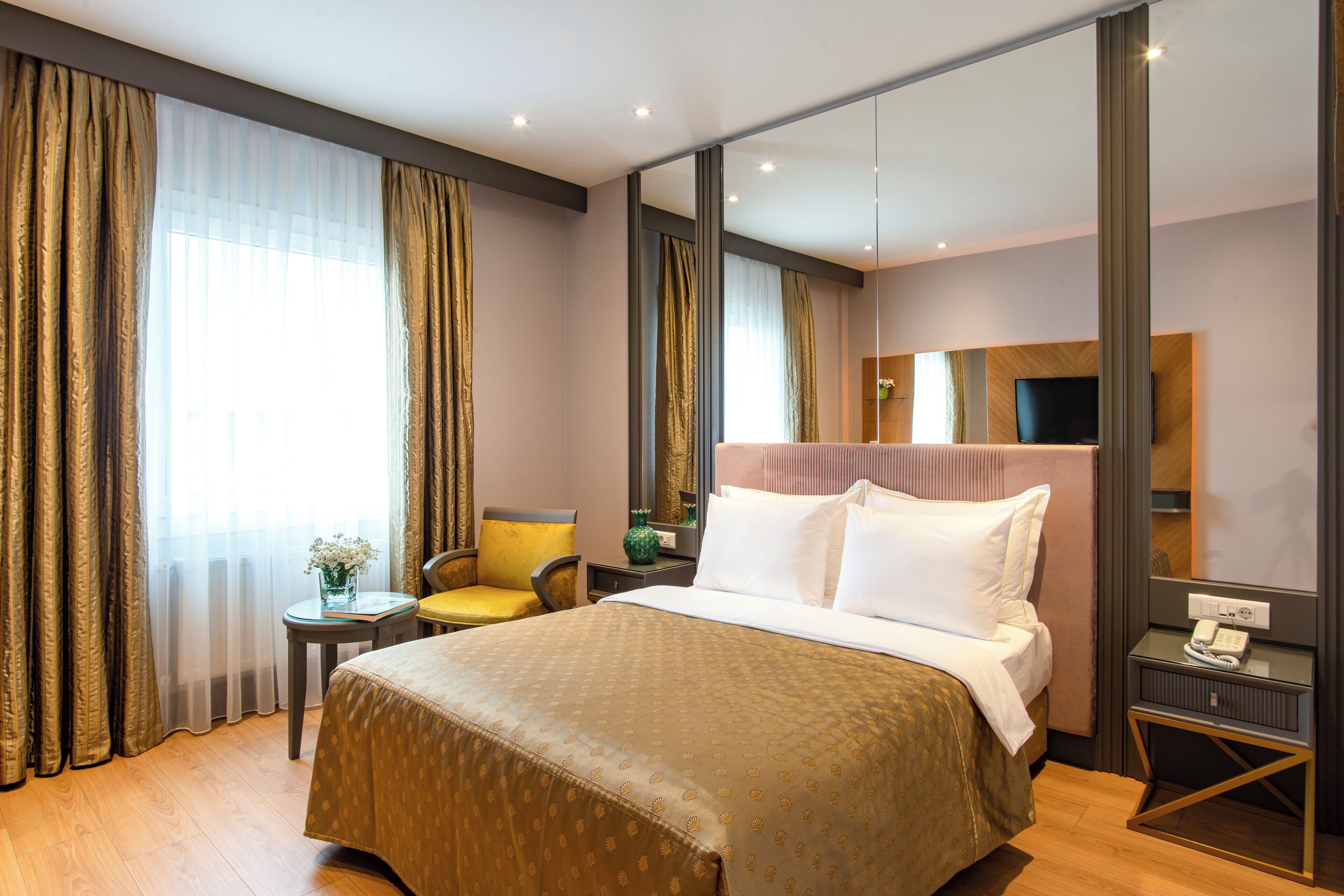 Une chambre d’hôtel avec un grand lit, une table de chevet avec un téléphone, une chaise et un téléviseur.