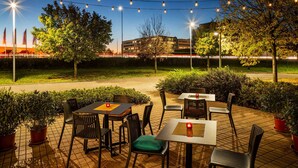 An outdoor patio area with tables and chairs, string lights, and potted plants. - Vienna House Easy by Wyndham Bratislava (Bratislava)