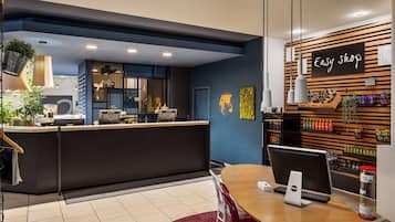 A modern reception area with a desk, a computer, and a seating area with a table and chairs.