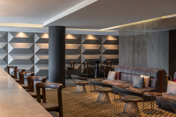 A modern lounge area with a long table, leather sofas, and patterned floor tiles. - Radisson Blu Okoume Palace Hotel, Libreville (Libreville)