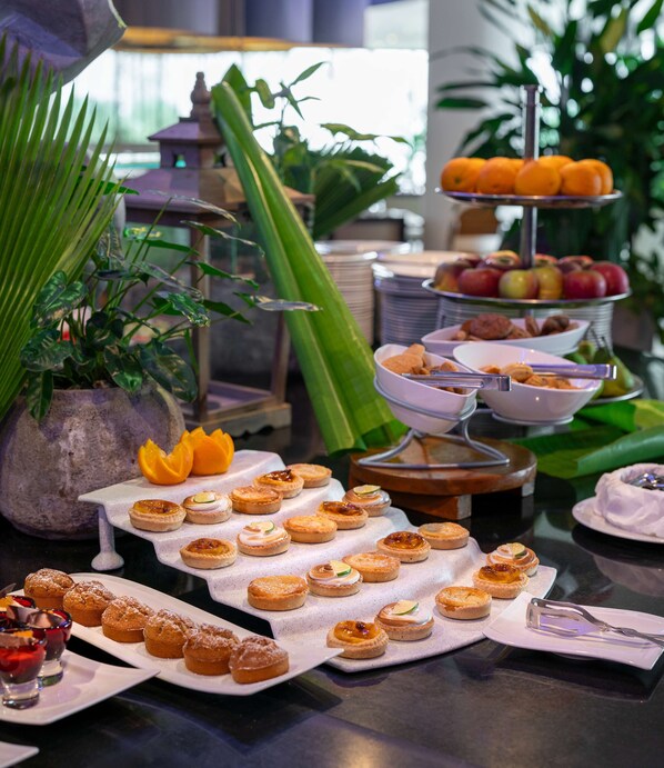 A buffet table with various food items, including pastries and fruits, arranged on tiered stands.