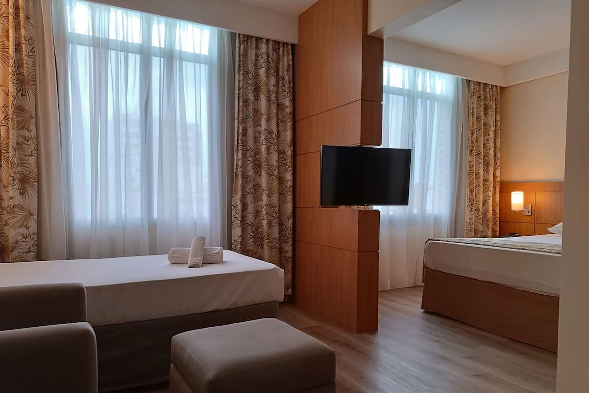 A hotel room with a bed, a sofa, a TV, and a desk.