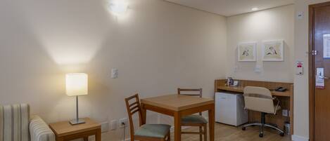 Un espacio habitable compacto con una mesa de comedor, dos sillas, una pequeña cocina americana y un sofá.