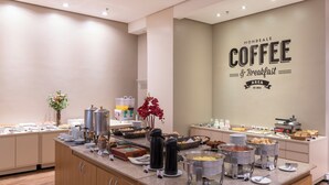 Un área de bufé con diversas opciones de comida y máquinas de café.