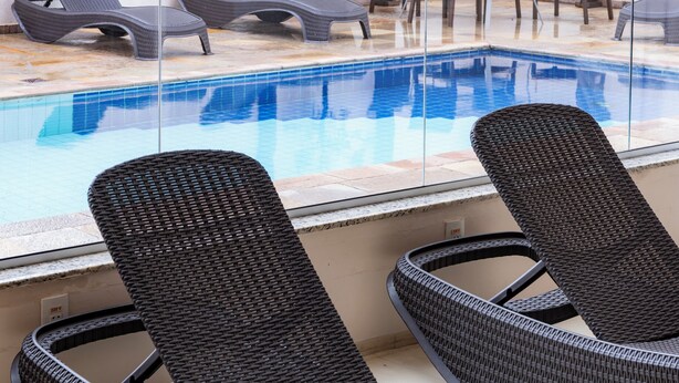 Un área junto a la piscina con sillones de mimbre y una mesa.