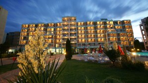 A multi-story hotel with a pool area, outdoor seating, and a well-lit facade. - Sirena Hotel (Sunny Beach)