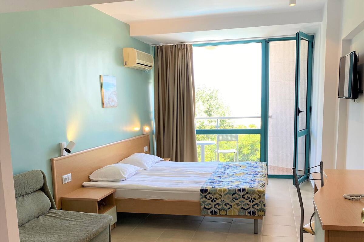 Une chambre d’hôtel avec un lit, un canapé, un bureau et un balcon offrant une vue.