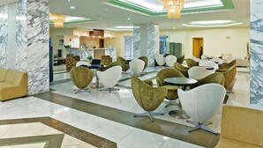 A modern hotel lobby with marble columns, a reception desk, and contemporary seating areas. - Marianna Palace (Rhodes)