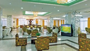 A spacious lobby with modern seating, a television, and a marble reception desk. - Marianna Palace (Rhodes)