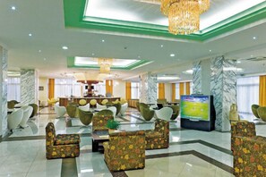 A spacious lobby with modern seating, a television, and a marble reception desk. - Marianna Palace (Rhodes)