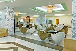 Un vestíbulo de hotel con columnas de mármol, asientos modernos y una zona de recepción.