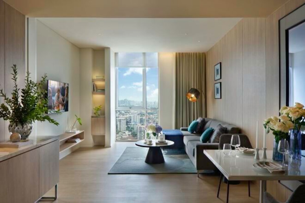 Una sala moderna con un sofá, una mesa de comedor, una mesa de centro y un amplio ventanal con vista a la ciudad.