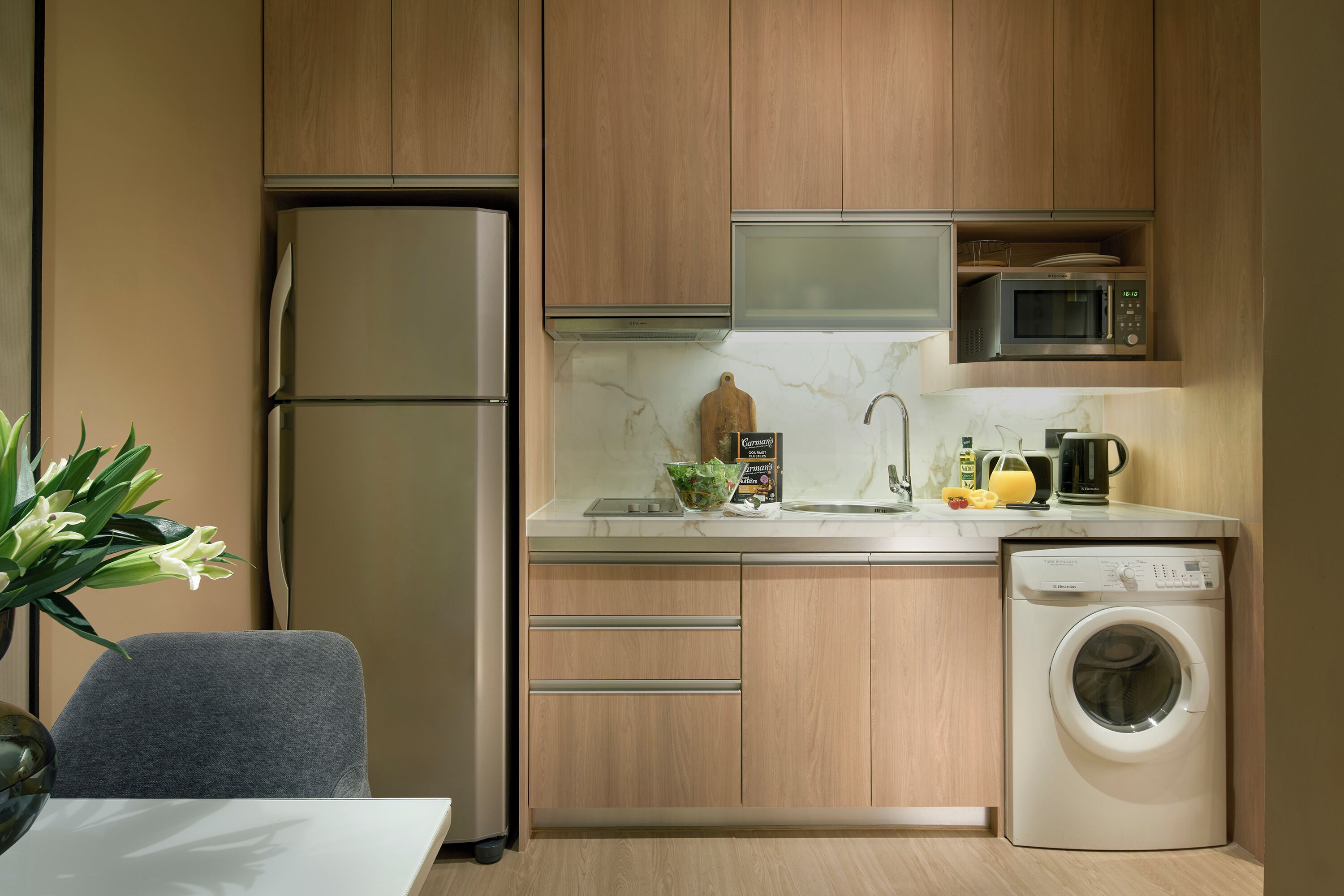 A compact kitchen with wooden cabinets, a built-in microwave, a dishwasher, and a sink.