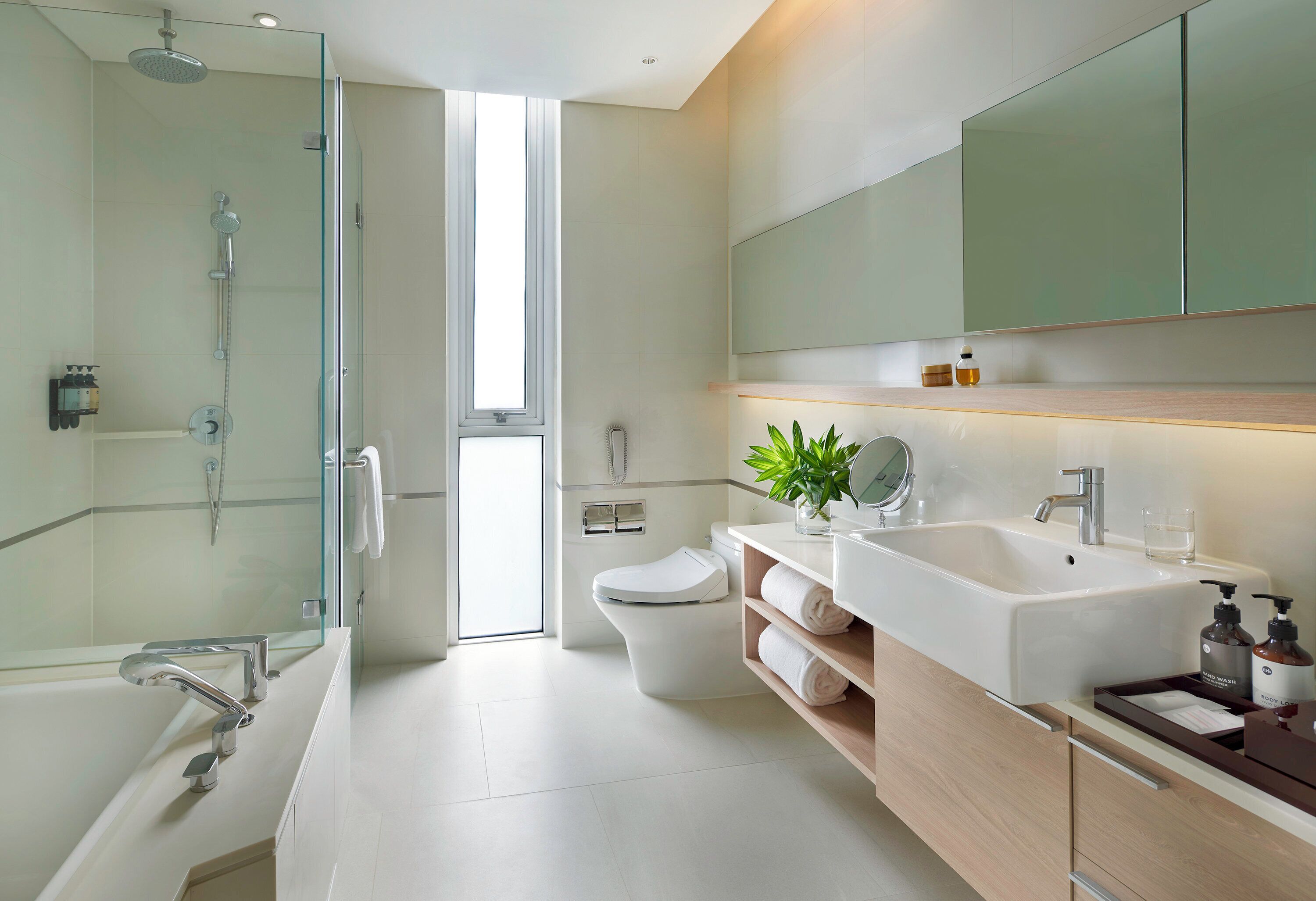 A modern bathroom with a glass-enclosed shower, a white toilet, and a large sink with a mirror above it.