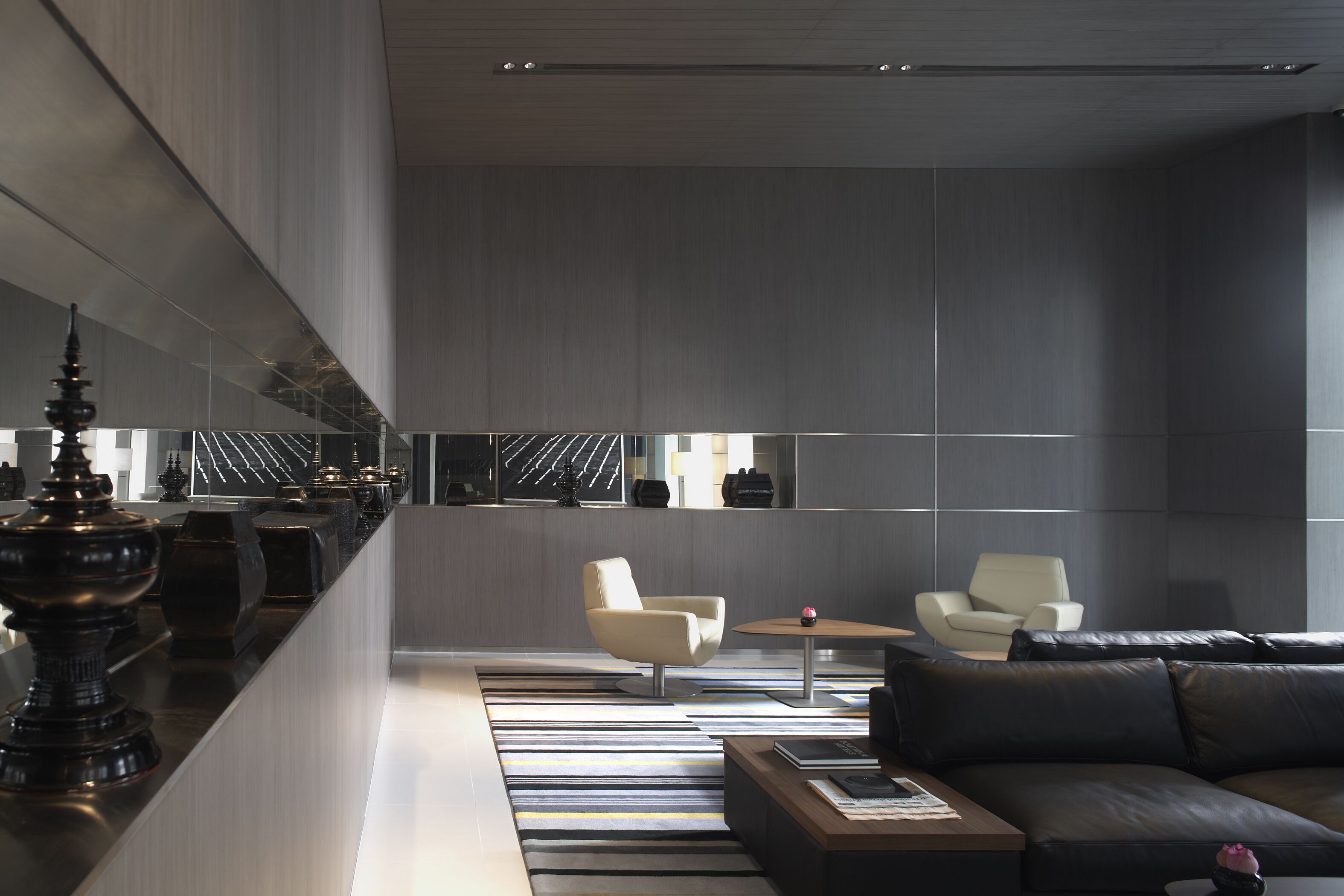 A modern interior with a sofa, chairs, a coffee table, and a decorative object on a counter.