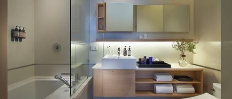 A modern bathroom with a glass-enclosed shower, a white sink, a wooden vanity, and a toilet.