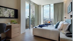 A modern hotel room with a large bed, a desk, and a chair. There is a large window with a city view. - Somerset Sukhumvit Thonglor Bangkok (Bangkok)