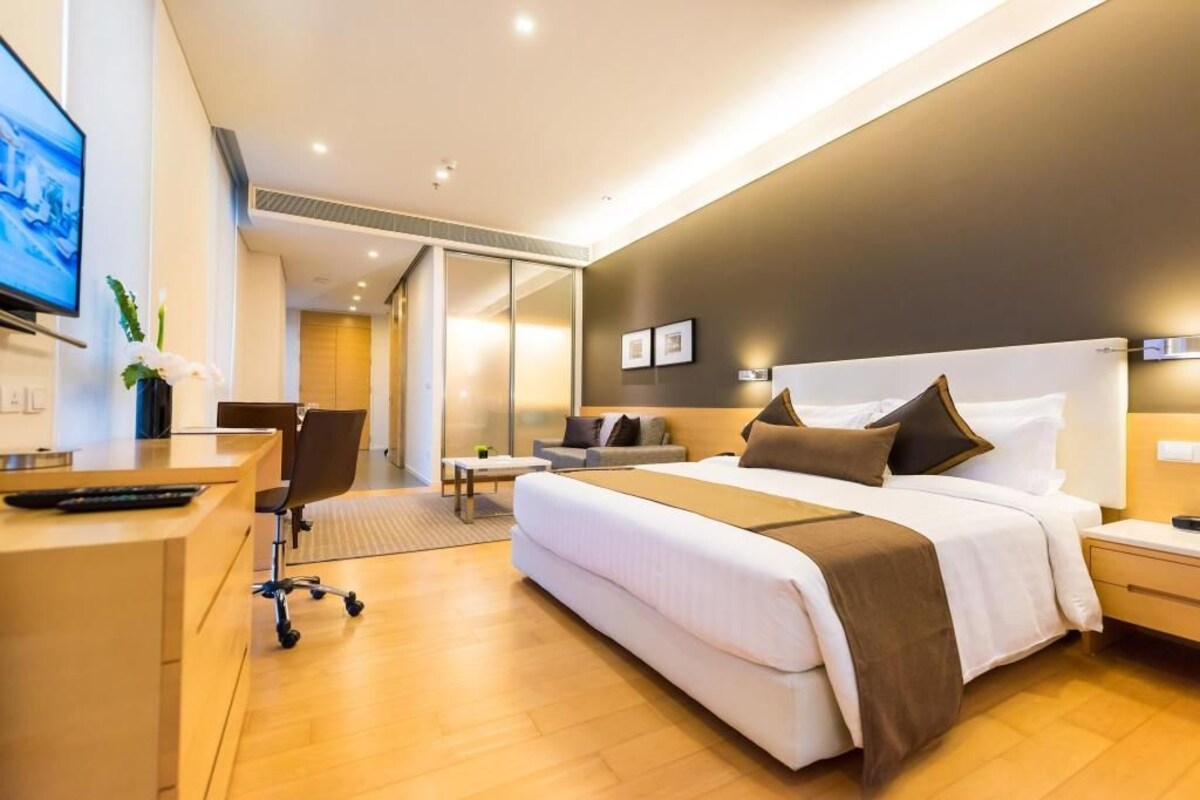 A modern hotel room with a large bed, a desk, a chair, and a television.