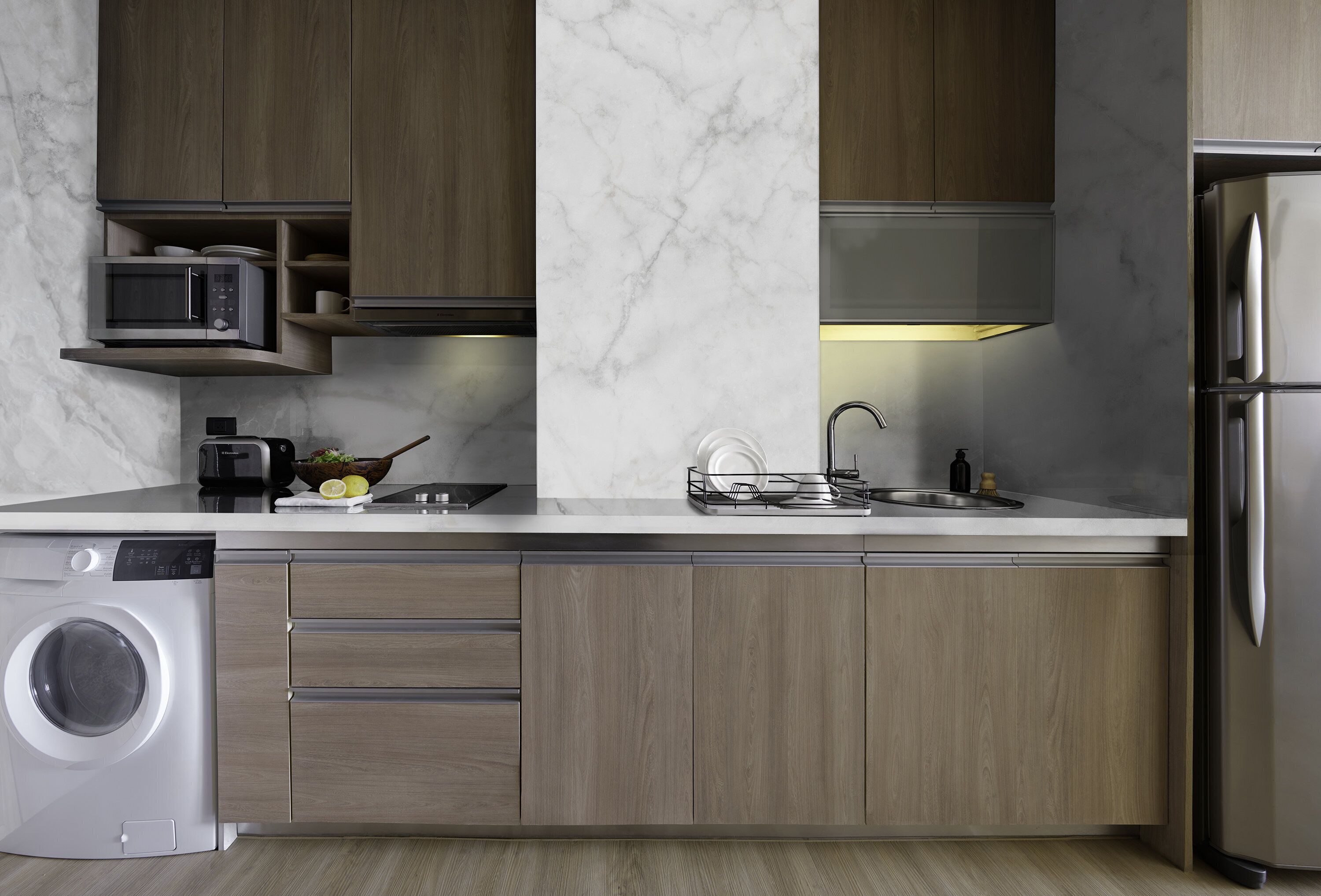Una cocina moderna con lavadora integrada, microondas y refrigerador de acero inoxidable.