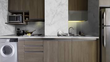 Una cocina moderna con lavadora integrada, microondas y refrigerador de acero inoxidable.