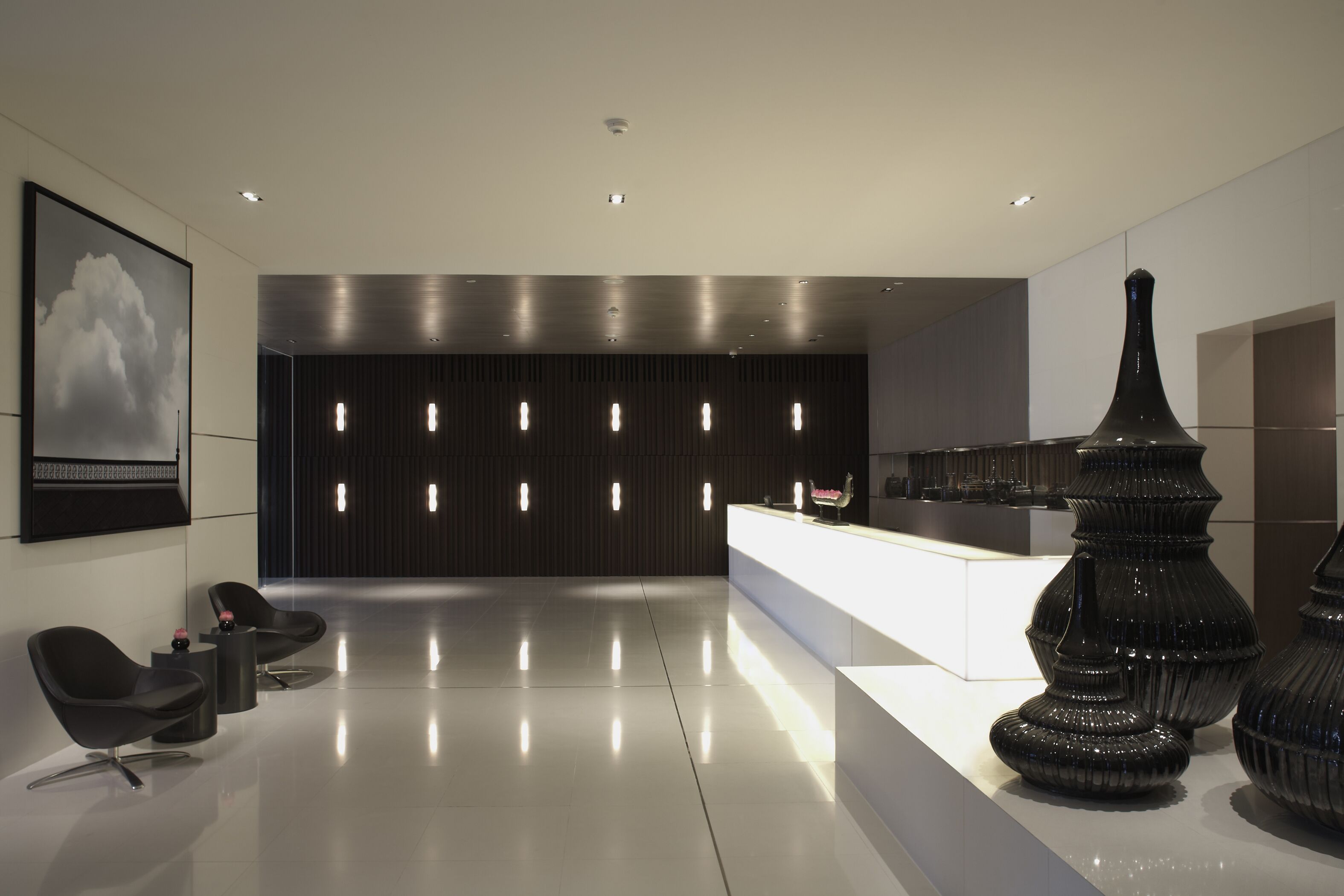 A modern lobby with a reception desk, black chairs, and decorative vases.