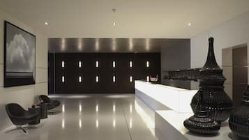A modern lobby with a reception desk, black chairs, and decorative vases.
