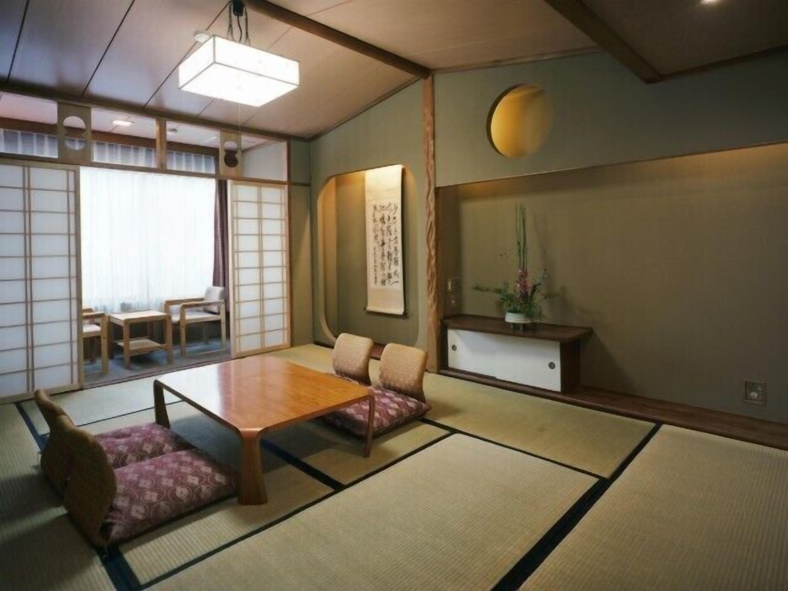 A traditional Japanese-style room with tatami flooring, a low table, and a seating area.