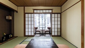 Une pièce de style japonais traditionnel, avec un sol recouvert de tatamis, une table basse et des chaises, ainsi que des paravents en papier de riz (shoji).