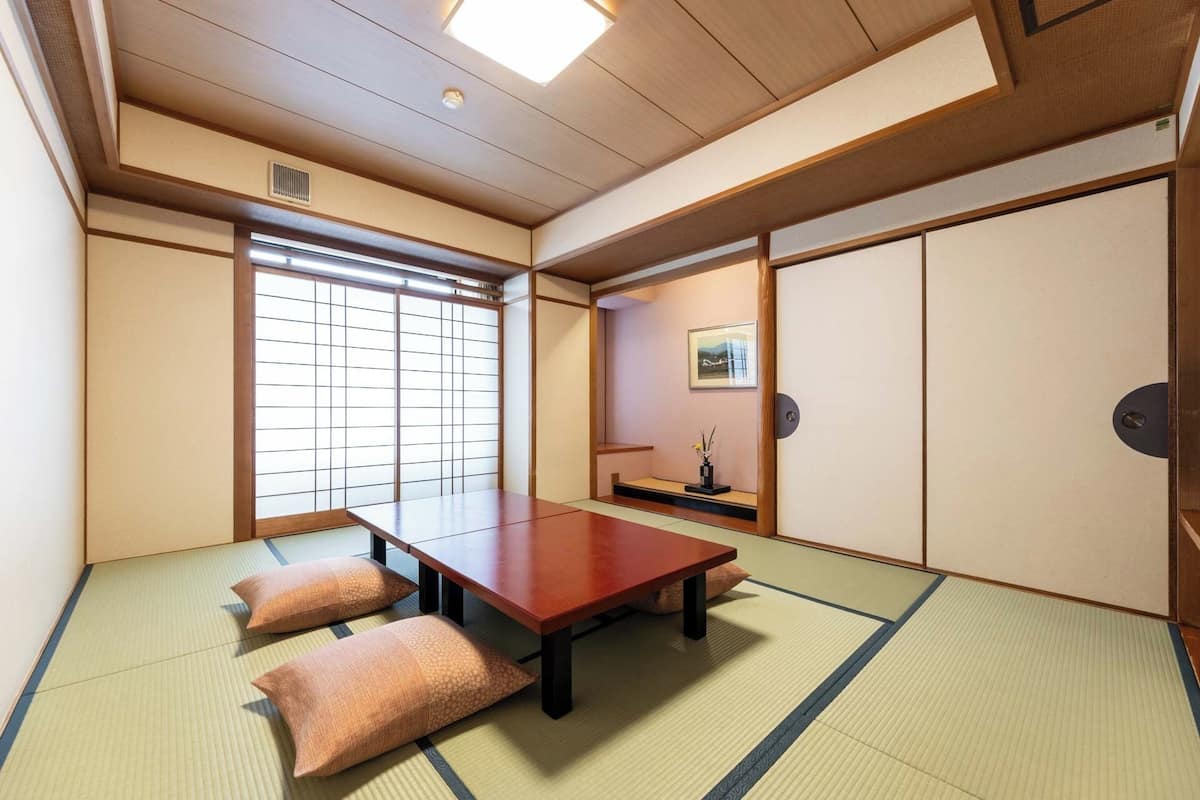 Una habitación japonesa tradicional con suelo de tatami, una mesa de madera baja y puertas correderas.