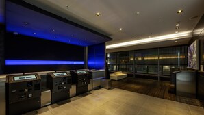 A modern lobby with a reception desk, self-service kiosks, and a seating area with a view of the city. - remm Akihabara (Tokyo)