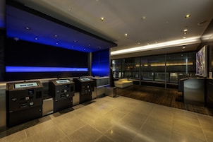 A modern lobby with a reception desk, self-service kiosks, and a seating area with a view of the city.