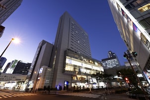 A modern building with a prominent glass facade, multiple floors, and a crosswalk in front.