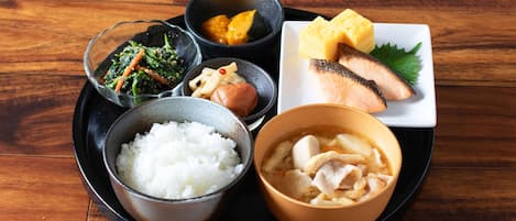 Una comida tradicional japonesa con arroz, pescado y diferentes acompañamientos sobre una mesa de madera.