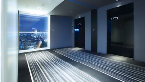 A modern hotel lobby with a large window offering a city view, a striped carpet, and a minimalist design. - remm Akihabara (Tokyo)