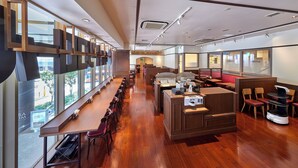 A modern restaurant with long communal tables, individual booths, and a view of the street. - remm Akihabara (Tokyo)