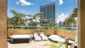 A rooftop terrace with two hot tubs, lounge chairs, and a champagne bottle.
