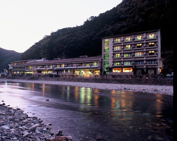 Un hôtel à plusieurs étages, doté d’une architecture moderne, situé au bord d’une rivière dont les rives sont rocheuses.