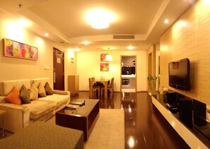 A modern living room with a sofa, coffee table, and a flat-screen TV mounted on the wall. - Somerset Jiefangbei (Chongqing)