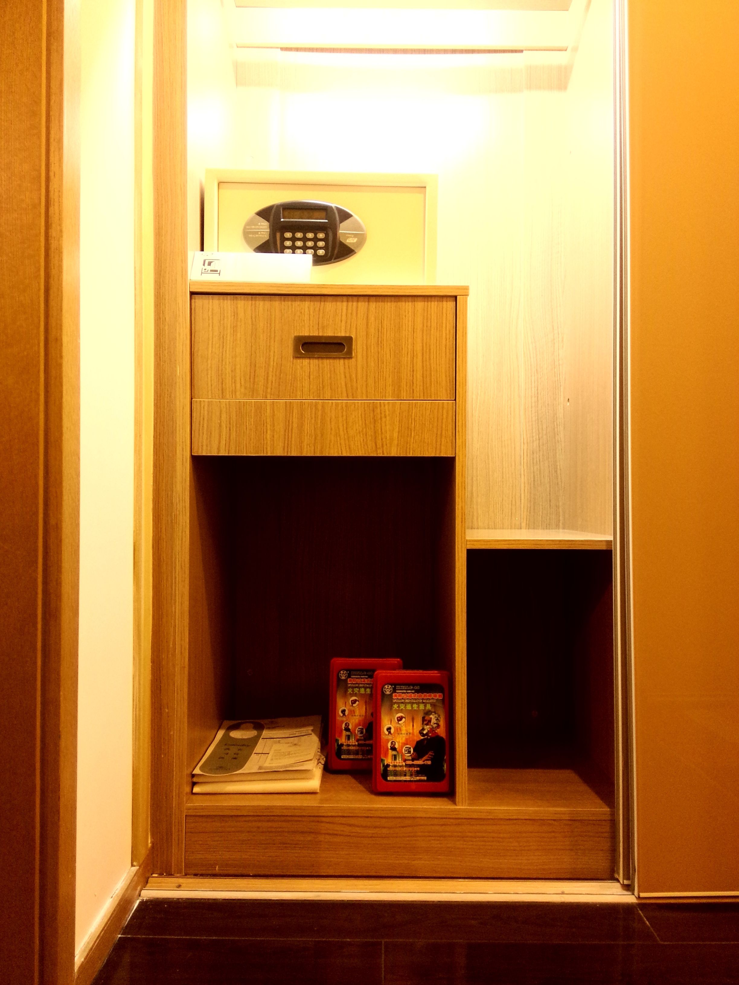 A small wooden cabinet with a telephone and two red boxes on a shelf.