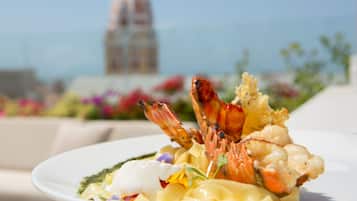 Un plato de mariscos con langostinos y vieiras, con un paisaje urbano de fondo.