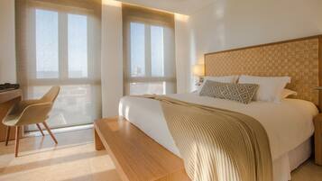 A modern hotel room with a large bed, a wooden desk, and a chair.