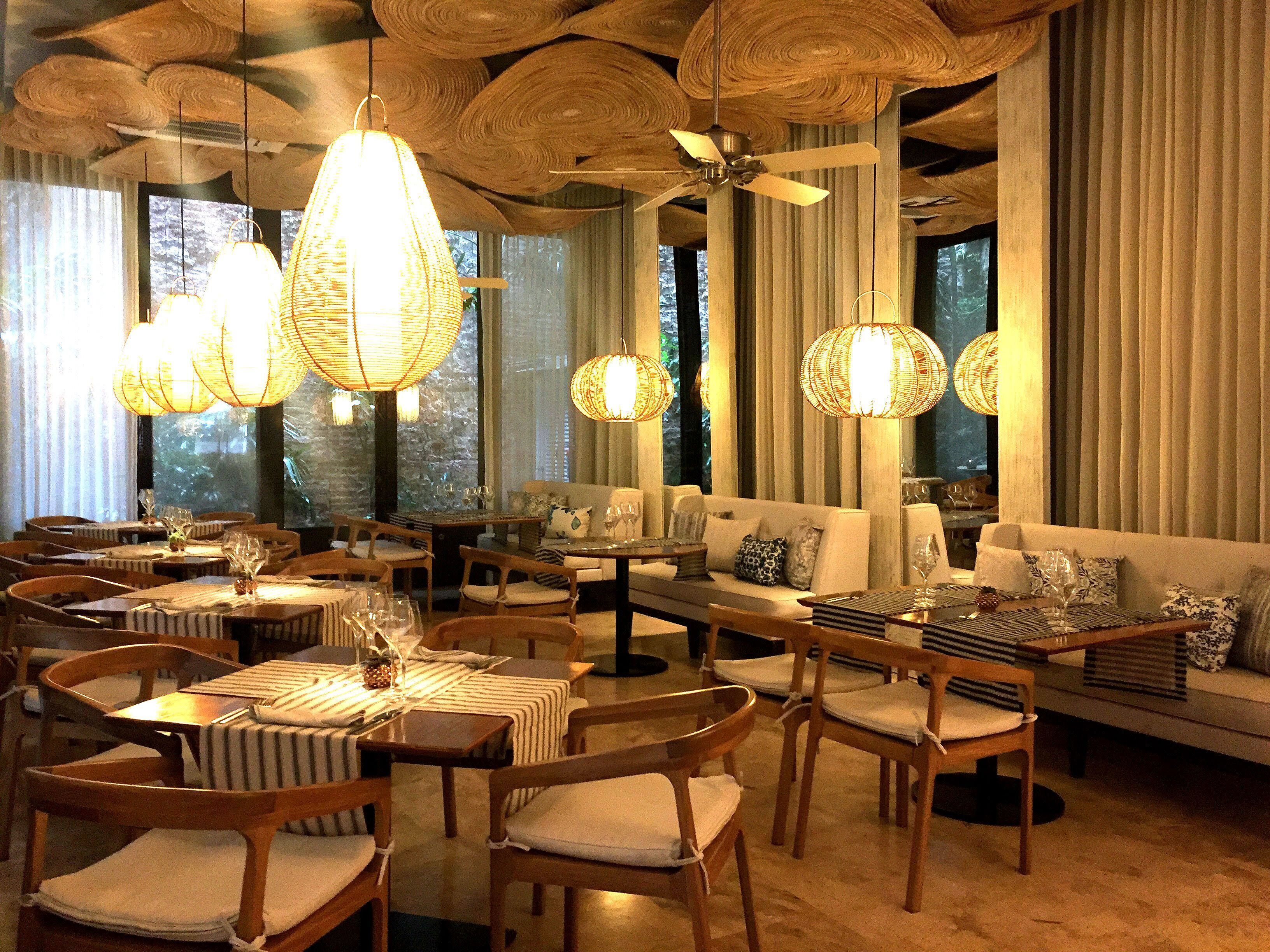 A spacious dining area with wooden furniture and hanging light fixtures.
