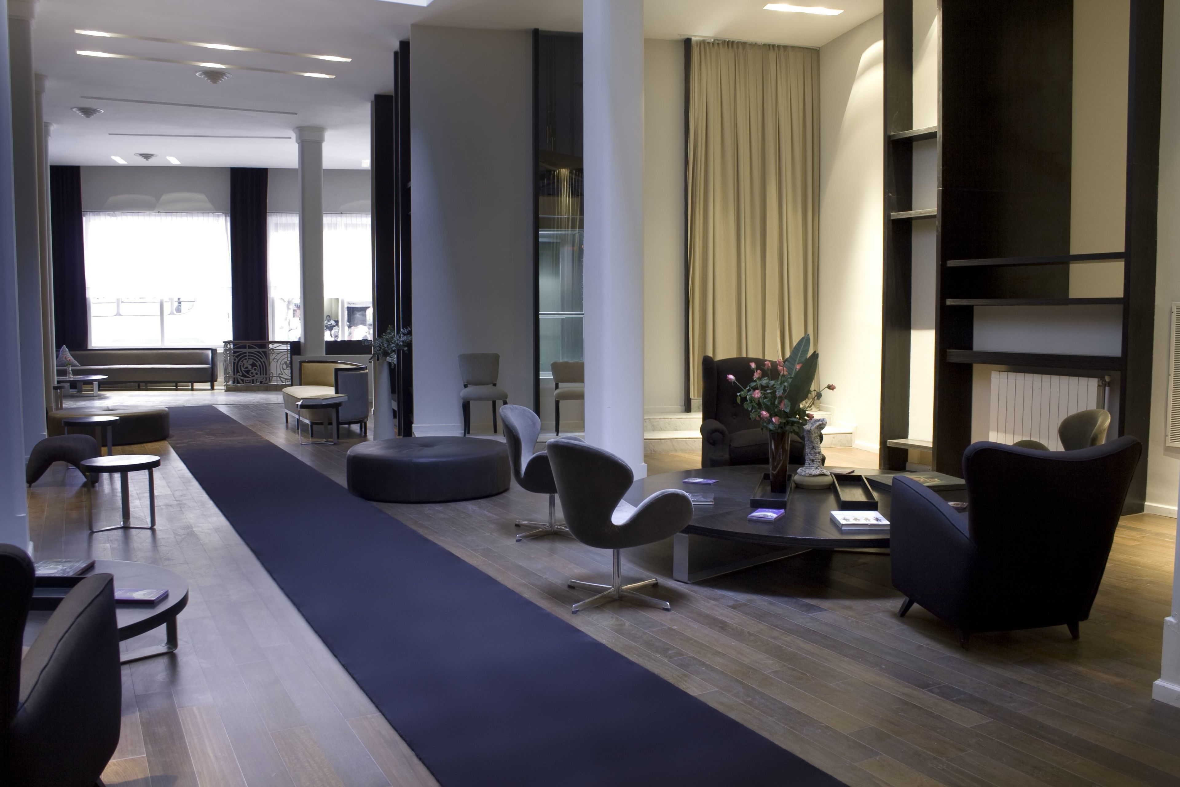 Uma área de estar moderna, com um tapete preto comprido, cadeiras contemporâneas, uma mesinha de centro e uma lareira.