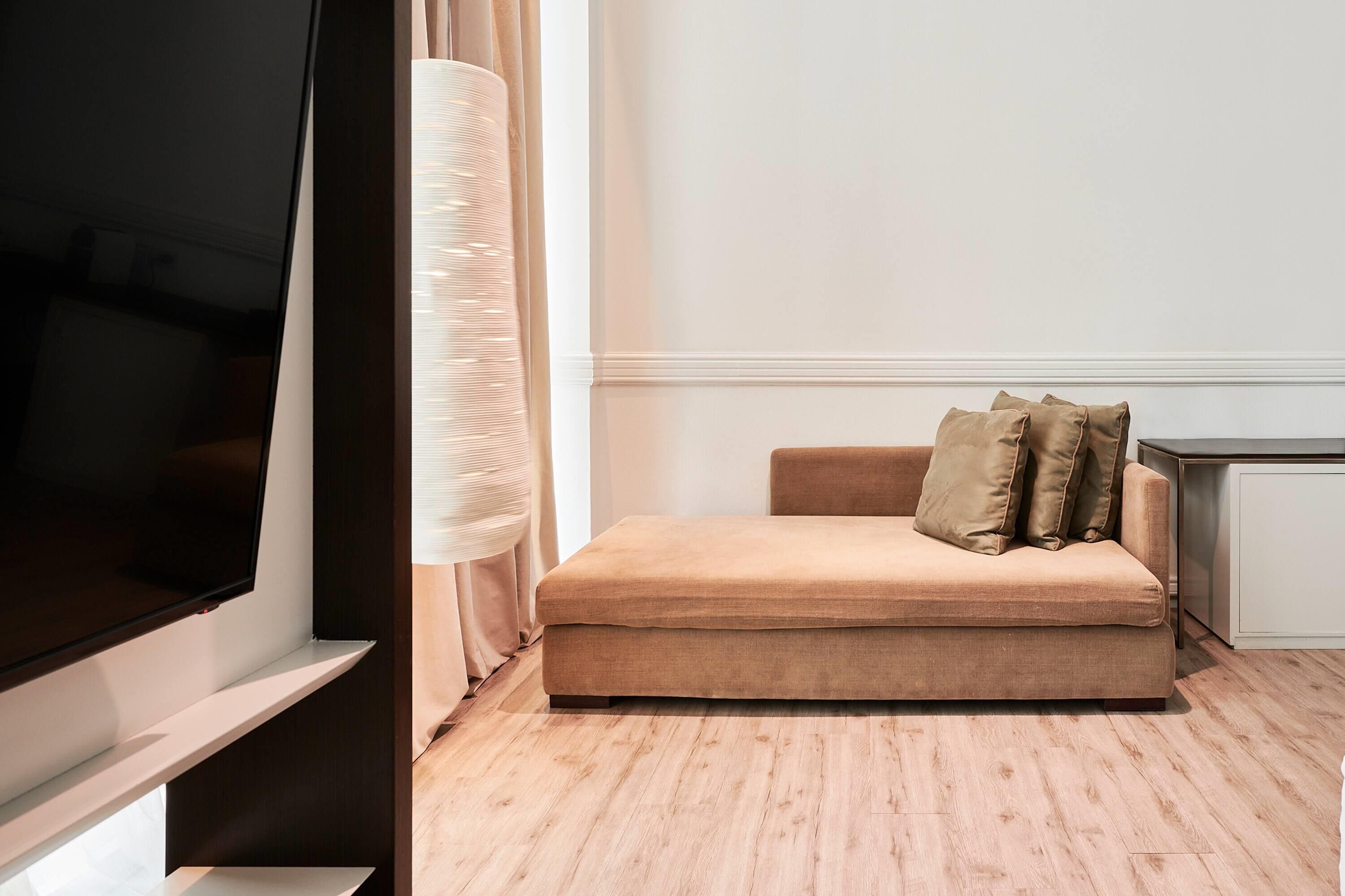 Un salon moderne avec un canapé beige, un téléviseur à écran plat et un plancher en bois.