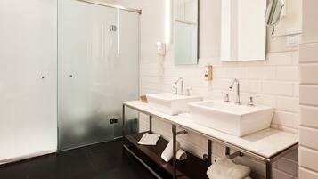 Een moderne badkamer met twee wasbakken, een glazen douchecabine en een badkamermeubel met een handdoekhouder.