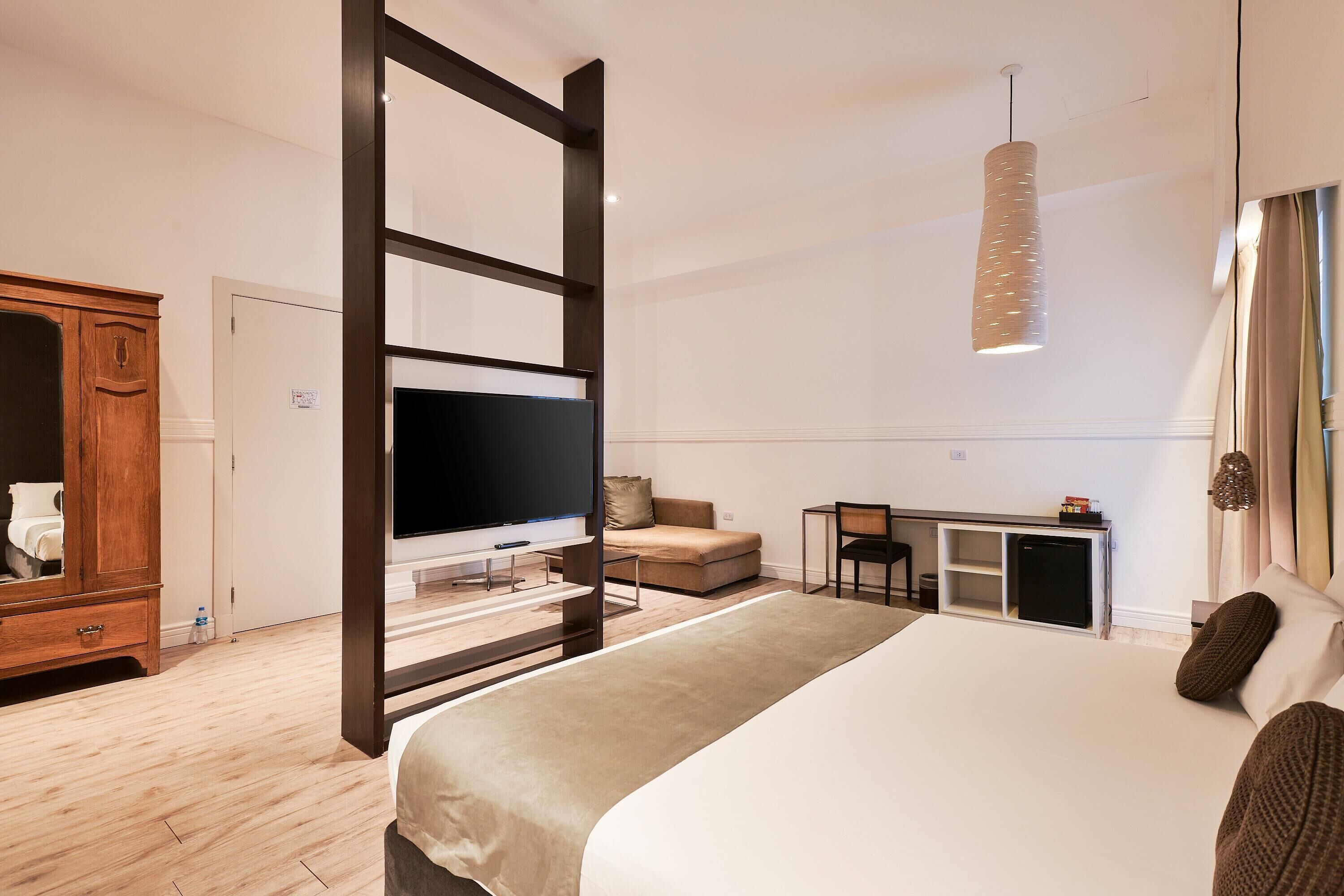 Una habitación de hotel moderna con una cama grande, televisión, escritorio y armario.