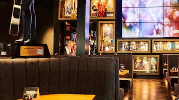Un restaurant où l’on trouve une grande statue d’une personne, des tableaux encadrés aux murs et une table en bois avec un menu.