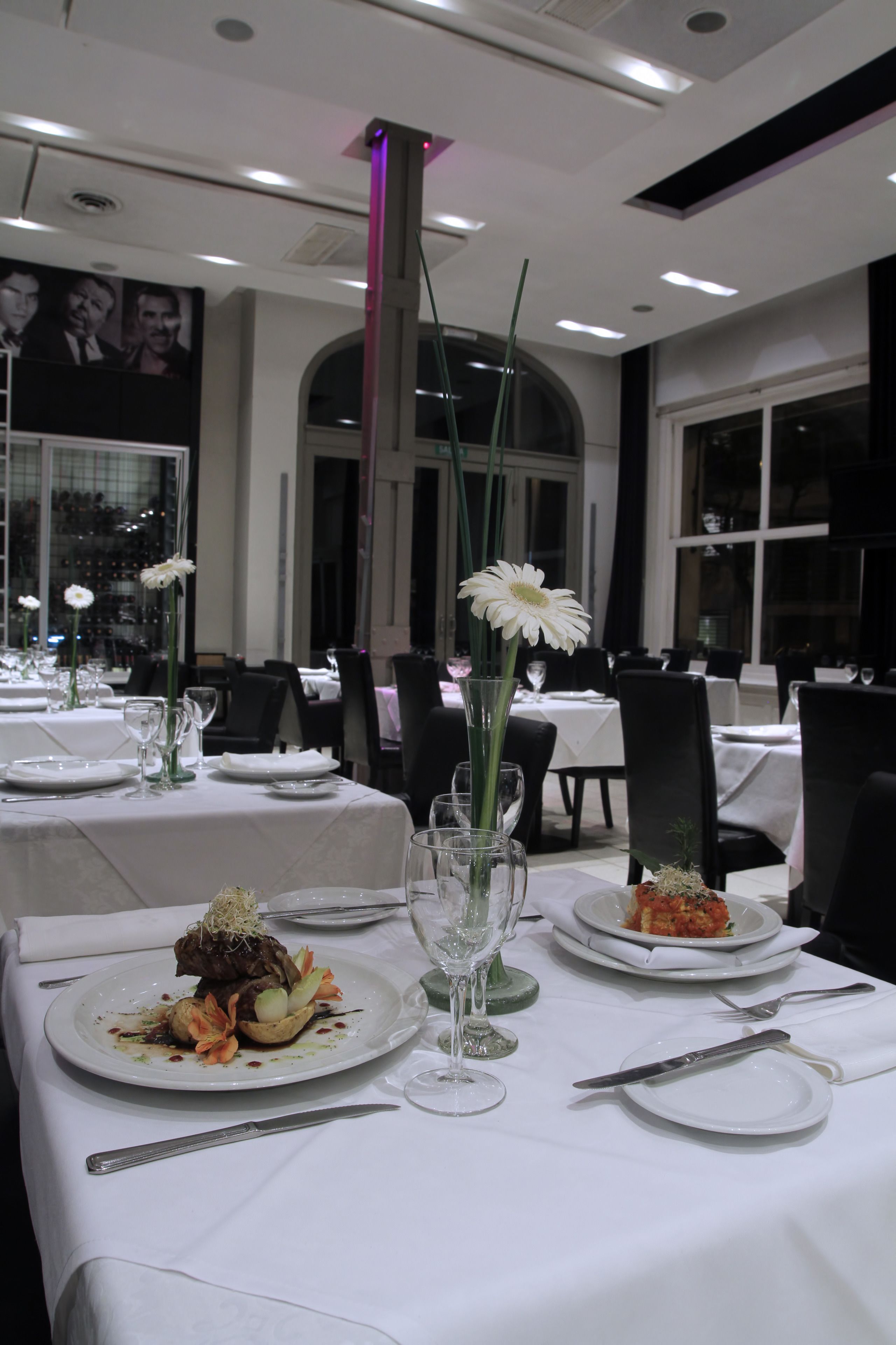 A restaurant with tables set for dining, featuring white tablecloths and elegant table settings.