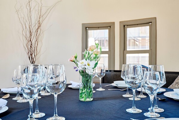 Una mesa de comedor dispuesta con varias copas de vino y un jarrón con flores.