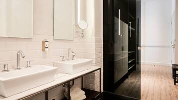 A modern bathroom with two sinks, a mirror, and a glass shower enclosure.